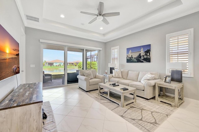 living room featuring a water view, ceiling fan, and a raised ceiling