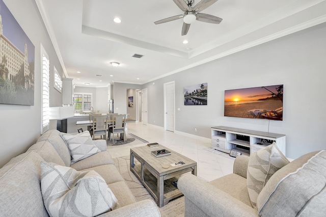 living room with ornamental molding, sink, ceiling fan, and a tray ceiling