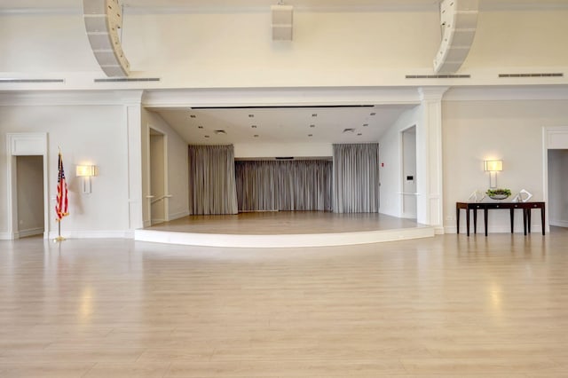 unfurnished living room featuring light hardwood / wood-style flooring and ornate columns