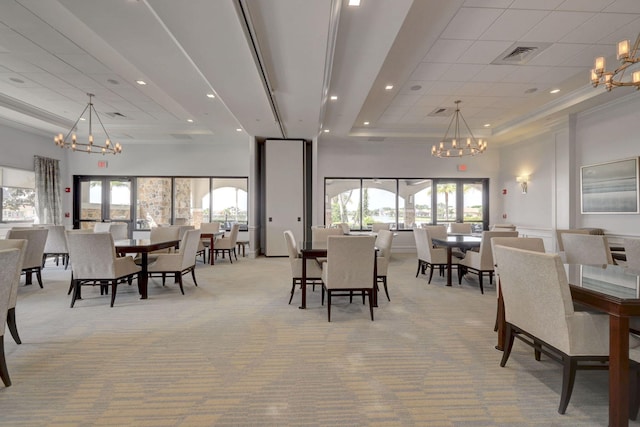 dining area with an inviting chandelier, light colored carpet, and a raised ceiling