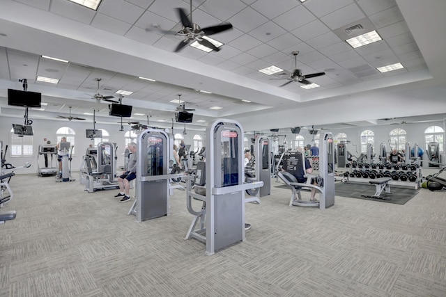 gym with light colored carpet, ceiling fan, and a tray ceiling