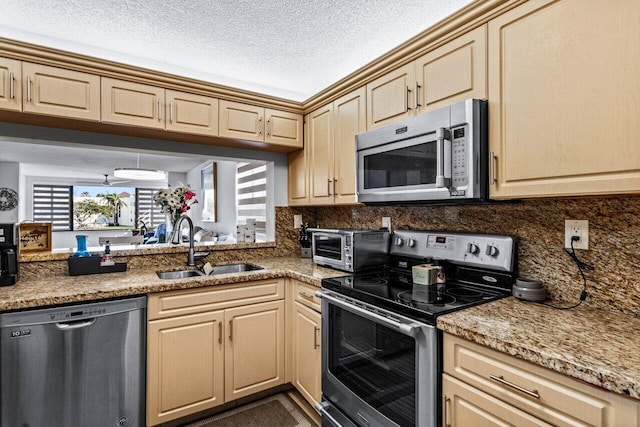 kitchen featuring sink, a textured ceiling, light brown cabinetry, light stone countertops, and appliances with stainless steel finishes