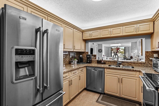 kitchen featuring light stone countertops, appliances with stainless steel finishes, tasteful backsplash, and sink