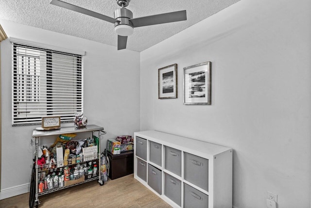 interior space with a textured ceiling, ceiling fan, and light hardwood / wood-style floors