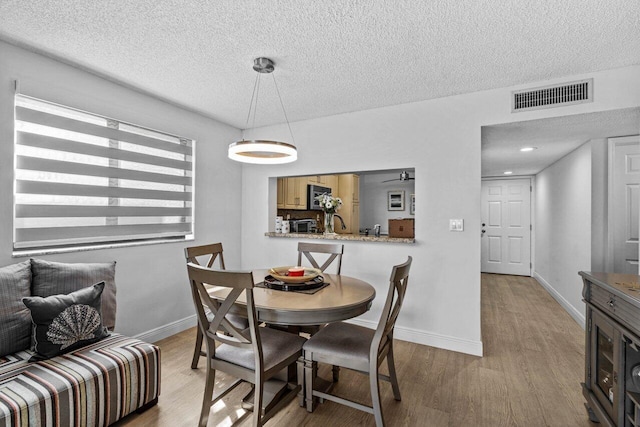 dining room with a textured ceiling and hardwood / wood-style floors