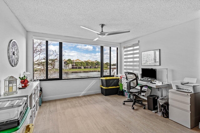 home office featuring ceiling fan, light hardwood / wood-style floors, a wealth of natural light, and a textured ceiling