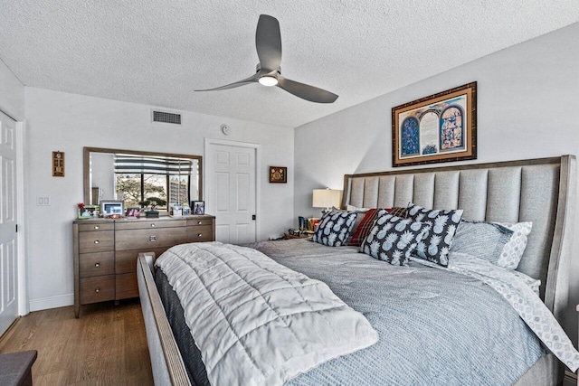 bedroom featuring dark wood-type flooring, a textured ceiling, and ceiling fan