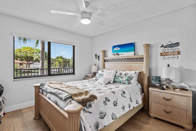 bedroom with ceiling fan, dark hardwood / wood-style flooring, and a textured ceiling