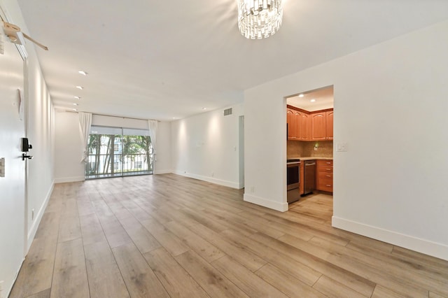 unfurnished living room with an inviting chandelier and light hardwood / wood-style flooring