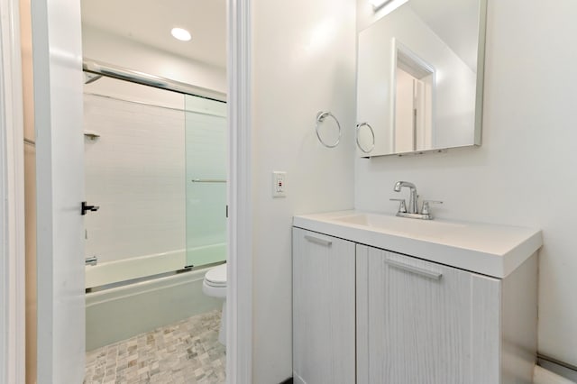 full bathroom featuring combined bath / shower with glass door, vanity, and toilet