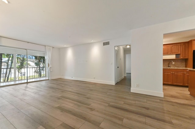 unfurnished living room with light wood-type flooring and sink