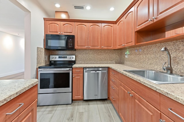 kitchen featuring backsplash, light hardwood / wood-style floors, sink, stainless steel appliances, and light stone counters