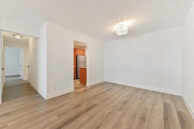 spare room with an inviting chandelier and light hardwood / wood-style flooring