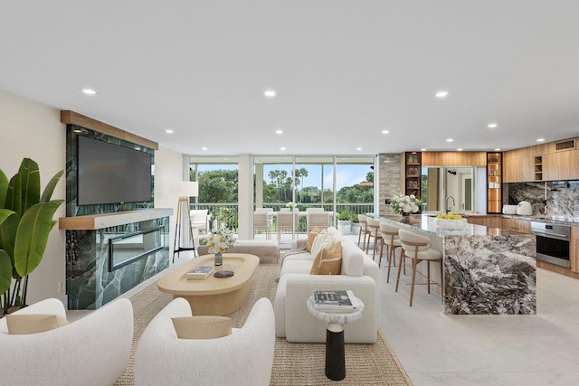 living room with floor to ceiling windows, a premium fireplace, and sink