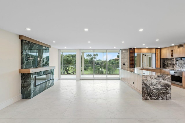 living room with floor to ceiling windows, a fireplace, and sink