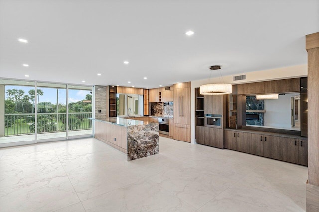 kitchen featuring light stone countertops, sink, stainless steel oven, and decorative light fixtures