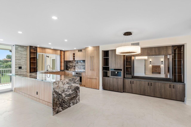 kitchen featuring sink, light stone counters, decorative light fixtures, oven, and decorative backsplash