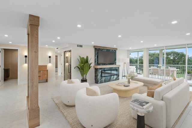 living room with a premium fireplace, floor to ceiling windows, and ornate columns