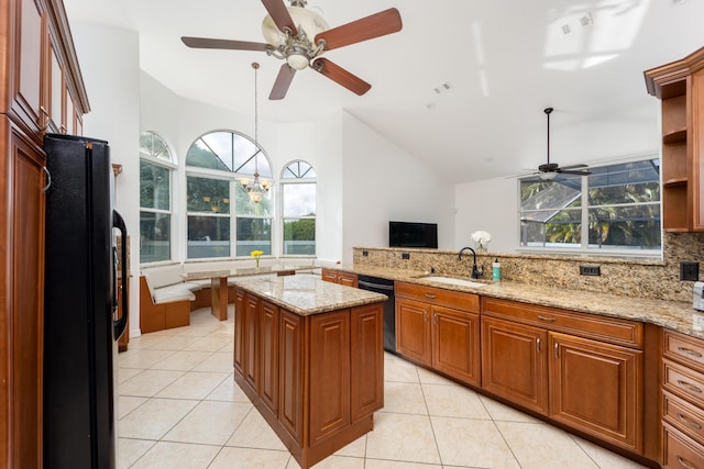 kitchen featuring light stone counters, black appliances, sink, a kitchen island, and light tile patterned flooring