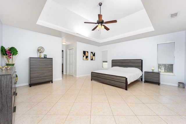 tiled bedroom featuring ceiling fan and a tray ceiling