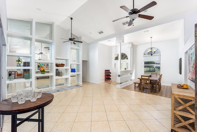 tiled living room with ceiling fan with notable chandelier and lofted ceiling