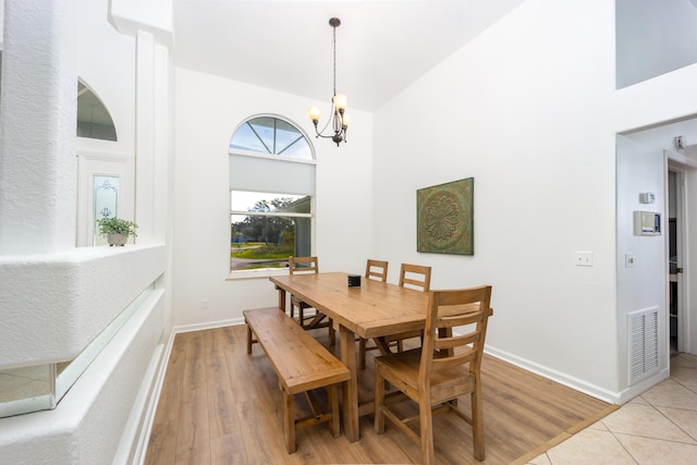 tiled dining space with a high ceiling and an inviting chandelier