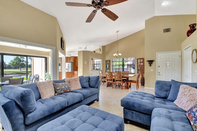 tiled living room with ceiling fan with notable chandelier and high vaulted ceiling