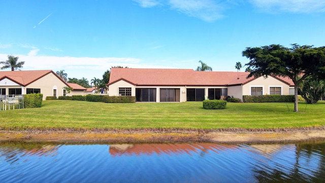 back of property featuring a water view and a lawn