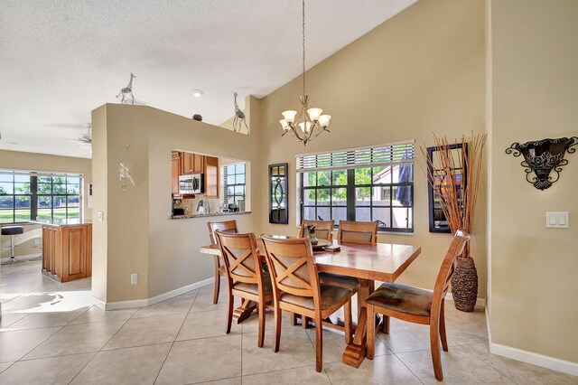 dining space with a textured ceiling, ceiling fan with notable chandelier, a wealth of natural light, and light tile patterned flooring