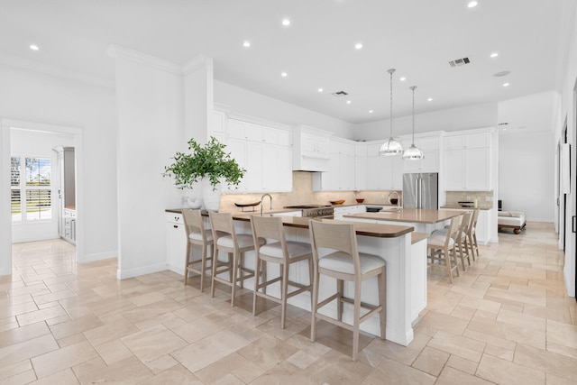 kitchen with pendant lighting, a breakfast bar, stainless steel appliances, a center island, and white cabinets