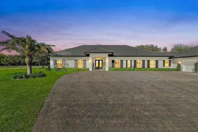 prairie-style home featuring a garage and a lawn