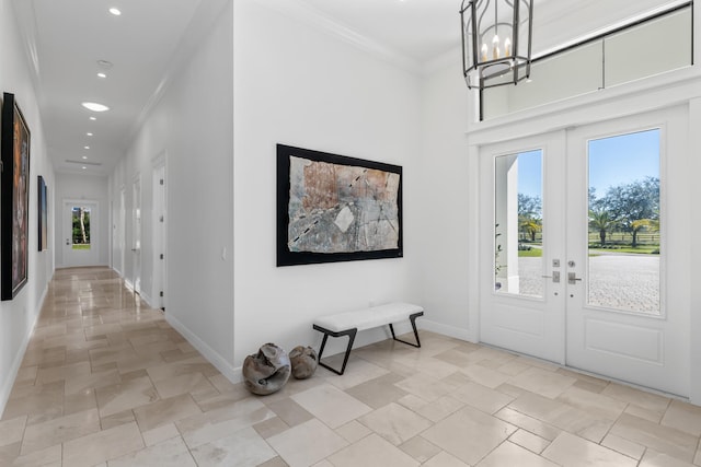 foyer with ornamental molding, french doors, and a notable chandelier