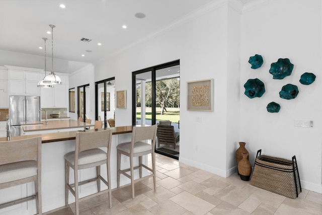 kitchen featuring decorative light fixtures, decorative backsplash, high quality fridge, a breakfast bar area, and white cabinets