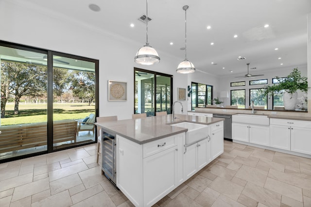 kitchen featuring stainless steel dishwasher, a kitchen island with sink, sink, and beverage cooler