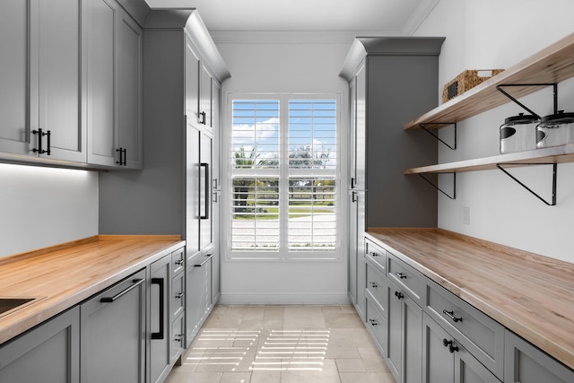 interior space with butcher block countertops, light tile patterned floors, gray cabinets, and crown molding