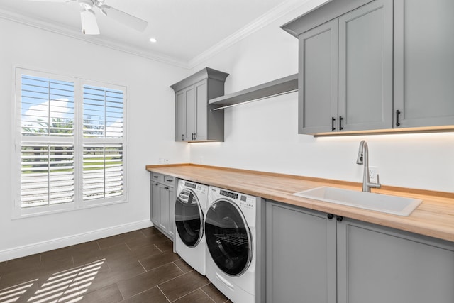 clothes washing area with ceiling fan, washing machine and dryer, sink, crown molding, and cabinets