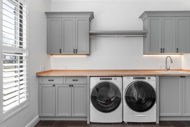 clothes washing area featuring cabinets, a wealth of natural light, washer and clothes dryer, and sink