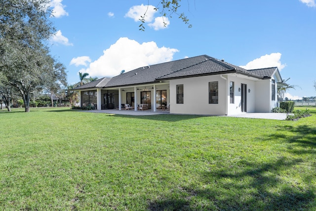 rear view of property with ceiling fan, a patio area, and a lawn