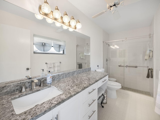 bathroom featuring vanity, toilet, a shower with door, and ceiling fan