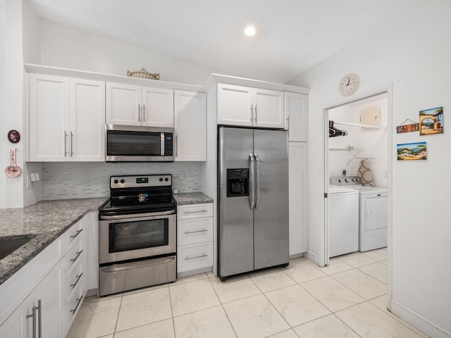 kitchen featuring white cabinetry, light stone countertops, stainless steel appliances, tasteful backsplash, and washer and clothes dryer