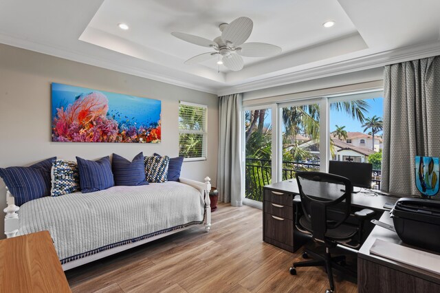 bedroom with light hardwood / wood-style flooring, a raised ceiling, and ceiling fan