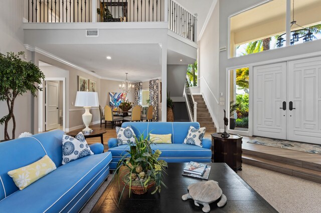 living room featuring a high ceiling, hardwood / wood-style flooring, ornamental molding, and a notable chandelier