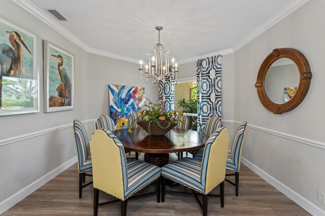 dining area with dark wood-type flooring, an inviting chandelier, and ornamental molding