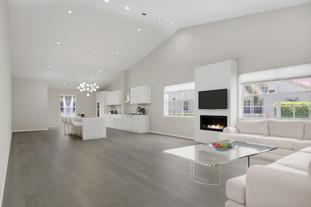 living room featuring high vaulted ceiling, wood-type flooring, and an inviting chandelier