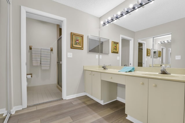 bathroom featuring vanity, a shower with shower door, and a textured ceiling