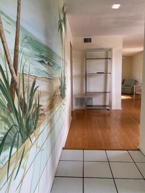 corridor with light tile patterned floors and a textured ceiling