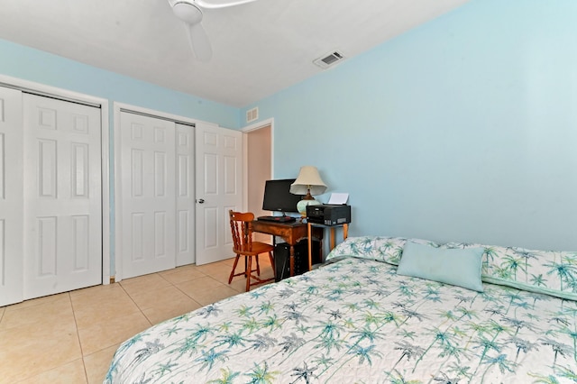 bedroom with ceiling fan, two closets, and light tile patterned floors