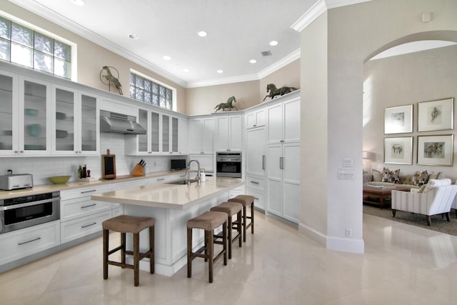 kitchen featuring white cabinetry, sink, oven, and a kitchen bar