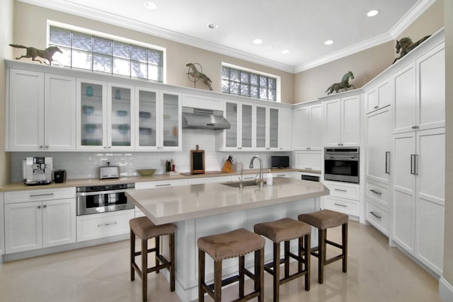 kitchen featuring white cabinetry, a kitchen breakfast bar, oven, and sink