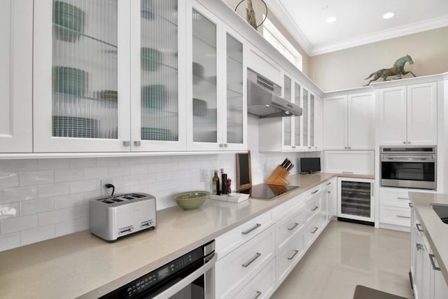 kitchen with white cabinetry, stainless steel oven, ornamental molding, beverage cooler, and wall chimney exhaust hood